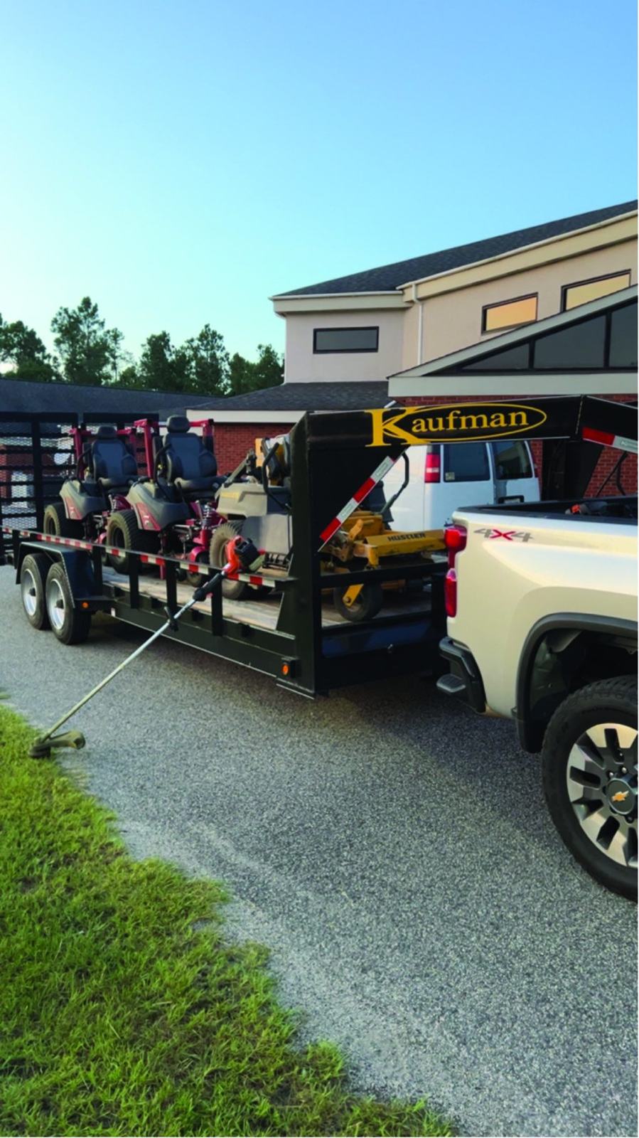 Zero-turn mowers on a gooseneck trailer at a school campus