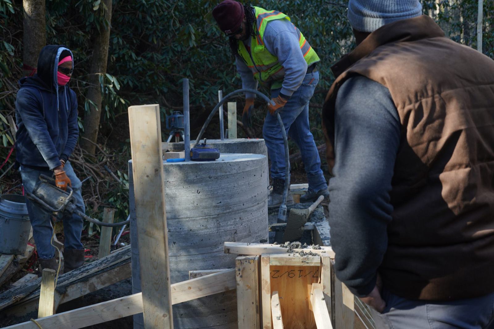 Crew pouring concrete piers for a bridge abutment